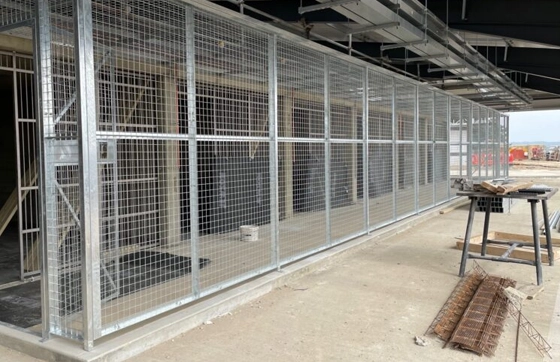 Very large secure galvanised mesh security cage with a mesh roof raised on a small concrete plinth