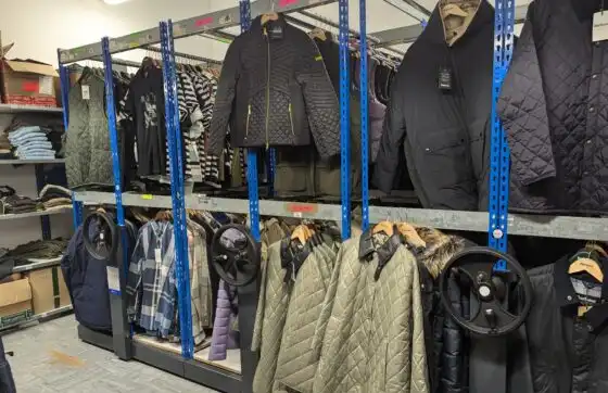 Mobile shelving used to store retail clothing in a compact mesh storage caged room